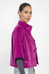 Chaqueta de terciopelo color fucsia, de corte recto y diseño corto. Presenta cuello alto, cierre frontal con botones y bolsillos laterales ocultos.