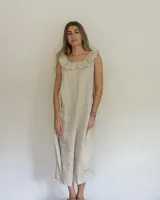 Vestido midi de lino color beige, de corte suelto, sin mangas y con escote redondo decorado con un volado amplio.
