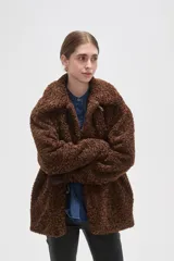 Campera de textura tipo corderito en color marrón, con cuello solapa y cierre frontal mediante tres botones tipo duffle con presillas de cuero sintético.