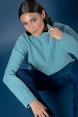 Buzo de cuello alto tejido en lana, con diseño de ochos en el centro y mangas largas con hombros caídos.