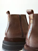 Bota corta de cuero en tonos chocolate, con diseño de paneles texturizados y suela track robusta de goma.