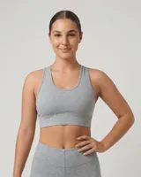 Top deportivo sin relleno, color gris claro, con breteles anchos y banda elástica inferior.