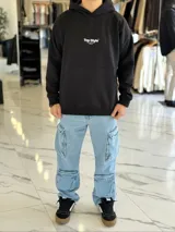 Canguro negro oversize con capucha y gran estampado blanco en la espalda con el texto "Top Style", "Dream big. Work hard. Make it real.", "SINCE 2021" y un código de barras.