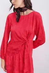 Vestido corto de viscosa jacquard color rojo, con escote redondo, mangas largas con puños elásticos y detalle de nudo drapeado en la cintura. Presenta un escote en V pronunciado en la espalda con cierre invisible.