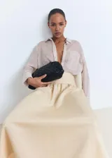 Falda midi evasé de tiro medio en color beige, con cintura entallada y bajo deshilachado.