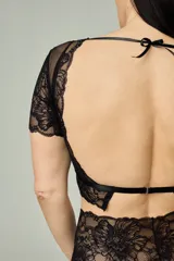 Conjunto de lencería negro compuesto por un bralette de lycra y microtul con detalles de encaje en escote, bajo busto y mangas cortas, y una bombacha hipster de tiro alto confeccionada íntegramente en encaje.