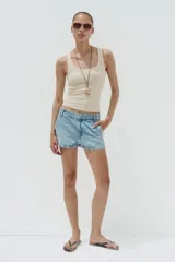 Shorts de denim de tiro medio, color celeste claro lavado, con trabillas, bolsillos laterales y bolsillos de plastrón en la espalda. Cierre frontal con cremallera y botón metálico.
