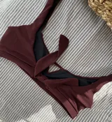 Top de bikini color bordó, con breteles anchos y abertura triangular en el centro del busto. Se ata en la espalda y tiene copas desmontables.