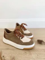 Championes de cuero color visón con cordones marrones, suela blanca y base color caramelo.