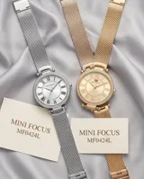 Reloj de pulsera Mini Focus con caja redonda plateada, bisel con incrustaciones de cristales y malla de acero tipo milanesa. Esfera minimalista con números romanos y movimiento de cuarzo japonés.
