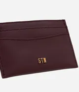 Tarjetera pequeña de poliuretano color bordó, con ranuras para tarjetas en la parte delantera y trasera, y logo metálico dorado aplicado en el frente.