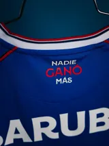 Camiseta de arquero Umbro del Club Nacional de Football, temporada 2026. Diseño en color azul con detalles en rojo y blanco en los hombros, cuello en V y estampado sutil en la tela. Incluye logo de Umbro, escudo del club, logo de la AUF y sponsor Antel en el frente.