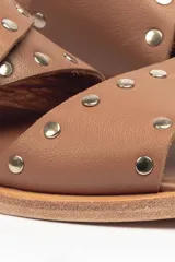 Sandalias bajas de cuero negro con tachas plateadas, tiras cruzadas y hebilla al tobillo.