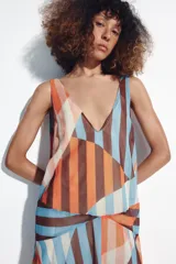 Vestido midi de tirantes con diseño geométrico y de rayas verticales en tonos salmón, celeste, marrón y blanco. Cuenta con escote en V y tirantes cruzados en la espalda.