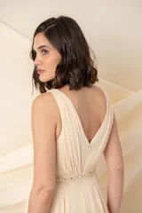 Vestido largo de gasa color champagne, con escote en V profundo y breteles anchos. Presenta una faja bordada con pasamanería y piedras en la cintura.