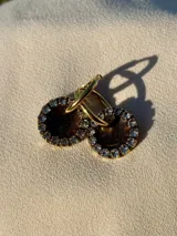 Aros de acero quirúrgico con dije circular de resina rosa y borde de strass dorados.