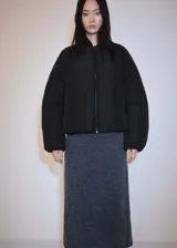 Chaqueta tipo bomber de diseño oversize en color negro, con cuello alto, cierre frontal de cremallera, bolsillos laterales y puños con elástico.
