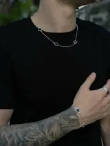 Collar de cadena tipo rolo con cinco dijes en forma de trébol de cuatro hojas con centro negro y borde plateado.
