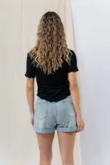 Short de jean azul claro con ruedo doblado fijo, tiro medio, calce cómodo, bolsillos delanteros y traseros, y cierre frontal con botón y cierre.