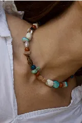 Collar corto de piedras naturales y cuentas multicolor en tonos turquesa, rojo, marrón y beige, con cierre de cadena ajustable.