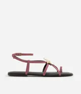 Sandalia plana color rosa con tiras finas, puntera redonda y adorno de estrella de mar dorada.