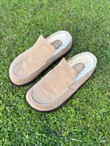 Zueco tipo mule de gamuza color beige, con interior forrado en piel sintética blanca y costuras decorativas en el borde superior.