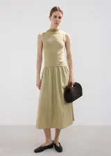 Vestido midi color tostado, con cuerpo superior de punto sin mangas con cuello alto y falda larga de tejido plano con vuelo.