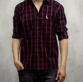 Camisa de manga larga a cuadros negros y rojos, con cuello clásico y cierre con botones.