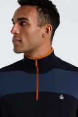Sweater de tejido de punto con diseño de rayas horizontales anchas en tonos azul marino y azul medio. Presenta cuello polo con cierre frontal de un cuarto con cremallera naranja. Tiene un pequeño logo de pingüino bordado en el pecho.