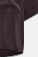 Camisa de cuello solapa y manga corta con dobladillo, presenta bolsillos de plastrón en el frente, bajo asimétrico y cierre frontal con botones ocultos.