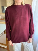 Sweater de punto acanalado color bordó, con cuello redondo, mangas largas con puños ajustados y diseño holgado con tajos laterales en el ruedo.