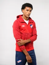 Campera deportiva Umbro del Club Nacional de Football, modelo Summit. Presenta un diseño con bloques de color en azul, rojo y blanco, con capucha, cierre frontal y bolsillos laterales con cierre. Incluye el logo de la marca y el escudo del club en el pecho.