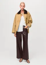 Pantalón de corte recto y tiro medio con efecto piel, diseño largo, trabillas en la cintura y cierre frontal de cremallera y botón, con cinco bolsillos.