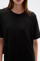 Remera negra de manga corta con textura acanalada, detalles de strass, cuello redondo y corte holgado.