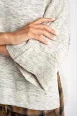 Sweater de punto con efecto jaspeado, de corte oversize, cuello redondo y mangas largas con terminación acampanada tipo volado.