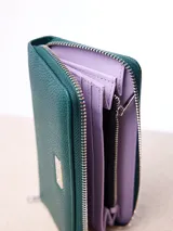 Billetera rectangular de cuero sintético con textura granulada, color bordó. Cuenta con cierre perimetral metálico y placa metálica con el logo de la marca en el frente.