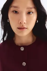 Chaleco bordó de punto interlock pesado, con cuello redondo y cierre frontal con botones de metal con acabado martillado.