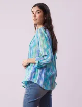 Blusa de gasa estampada multicolor, marca Ruby Rd. Tiene cuello a la base, escote en V, abertura central con botones y plisados en la parte delantera. Las mangas son 3/4 y tienen un largo regulable con presilla y botón.