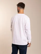 Remera blanca de manga larga con cuello redondo y logo bordado de un pájaro en el pecho.