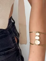 Brazalete de brazo dorado con tres dijes circulares de nácar.