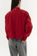 Camisa blanca de mangas dolman, cuello mao y pliegues en los hombros.