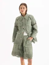 Bermuda estilo cargo confeccionada en gabardina color verde militar, de silueta recta y largo por encima de la rodilla, con múltiples bolsillos y detalles de encaje a tono en las piernas y el ruedo.