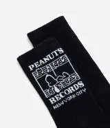 Medias de caña larga color negro, confeccionadas en tejido de algodón. Presentan un diseño estampado en la parte superior de la caña con el logo de Peanuts Records y la figura de Snoopy en color blanco.