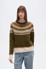 Sweater de poliéster color verde oliva con diseño geométrico en blanco, beige y marrón. Tiene cuello redondo, corte al cuerpo y detalles de cuentas en el cuello.