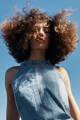 Vestido corto de denim con cuello halter, espalda descubierta y diseño de lavado combinado en tonos de azul.