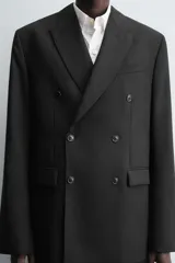 Blazer de corte regular confeccionada en tejido de lana italiana. Presenta cuello con solapas de pico, cierre frontal de botonadura cruzada, manga larga con puños abotonados, bolsillos de vivo en el pecho y bolsillos de solapa en la cadera.