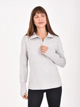 Buzo deportivo gris claro con cuello alto y cierre frontal parcial. Tiene mangas largas con orificios para los pulgares y costuras decorativas que realzan la figura.