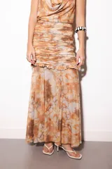 Falda larga de microtul con estampado tie-dye en tonos marrones y beige, diseño de tiro alto con frunces en la parte superior, volado horizontal y caída fluida transparente.