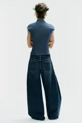 Top entallado de efecto denim, con cuello subido, manga corta, cierre frontal con botones y una llamativa abertura circular en el pecho.