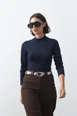 Polera de tejido de punto color celeste, con cuello alto y textura de pequeños puntos en relieve formando una cuadrícula en el frente y las mangas. De corte ajustado y manga larga.